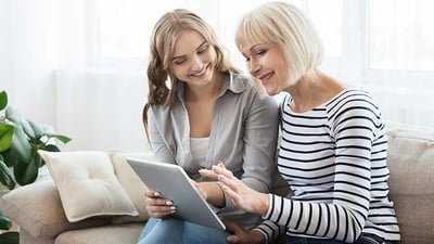 daughter-teaching-senior-mother-to-use-tablet-computer